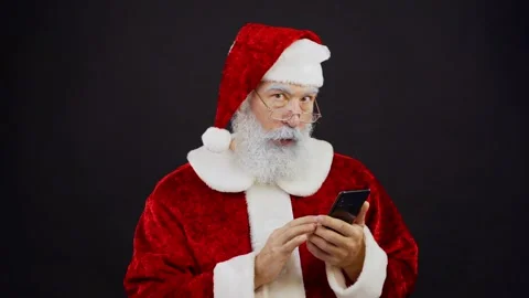 Surprised Santa browsing through messages on phone Stock Footage 139284940