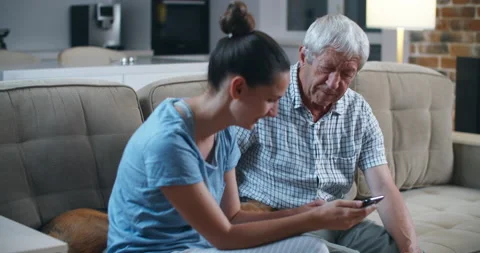 Surprised senior bearded father using smartphone while sitting on the gray sofa Stock Footage 135607423