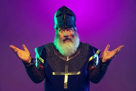 Surprised senior grey-bearded man in image of medieval warrior or knight in Stock Photos