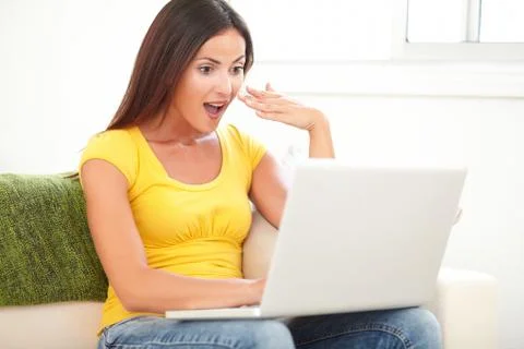 Surprised student using a laptop while sitting in the sunlight - indoors Stock Photos