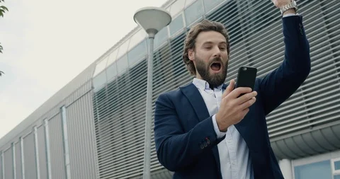 Surprised winner won online looking at his Phone sincerely laughing.  Stock Footage 117690323