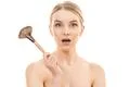 The surprised woman holding a cosmetic brush on the white background Photo