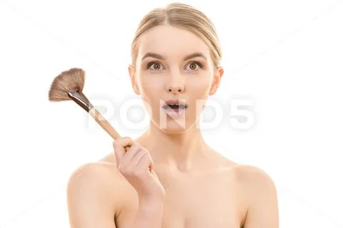The surprised woman holding a cosmetic brush on the white background Stock Photos