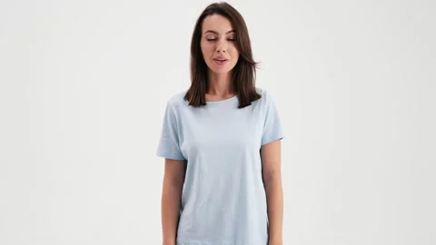 A surprised woman wearing basic t-shirt is standing in the studio 스톡 동영상 157866945
