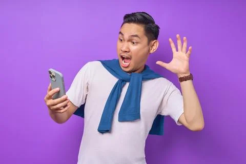 Surprised young Asian man using smartphone and reading special offer isolat.. Stock Photos