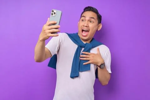 Surprised young Asian man using smartphone, reading special offer isolated .. Stock Photos