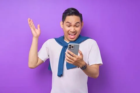Surprised young Asian man using smartphone, reading special offer isolated .. Stock Photos