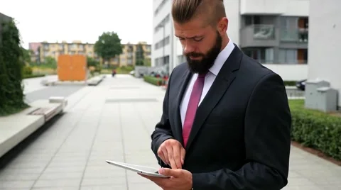 Surprised young bearded businessman using his tablet pc. Outdoor photo Stock Footage 56526631