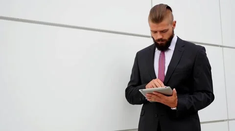 Surprised young bearded businessman using his tablet pc. Outdoor photo. Stock Footage 60944919