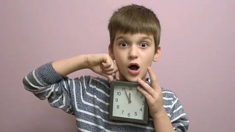 Surprised young boy with a clock Stock Footage 99242308