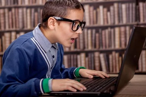 Surprised young  boy in the library with computer Stock Photos