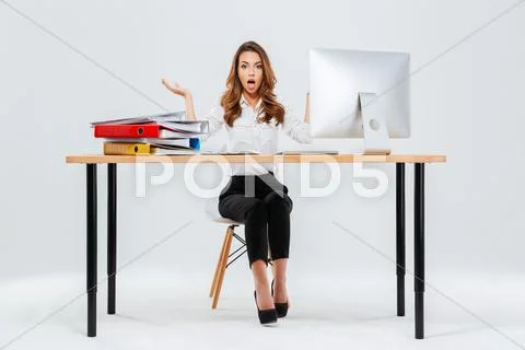 Surprised young businesswoman sitting at the table with pc Stock Photos