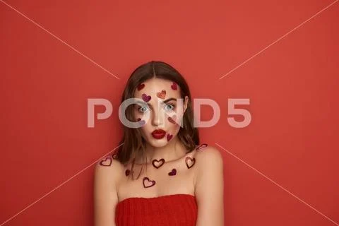 Surprised young lady with decorative hearts on body pouting her lips indoors Stock Photos