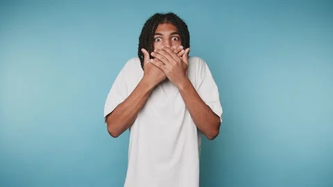 Surprised young man covers his mouth in shock, conveying a sense of disbeli.. Stock Footage 313280003