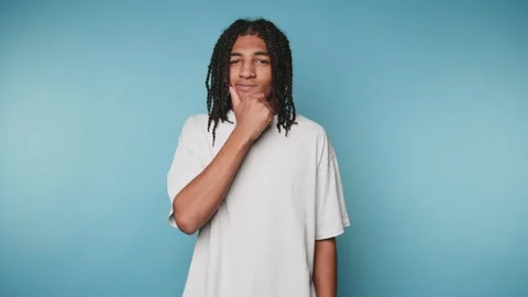 Surprised young man expresses shock while standing against a blue background Stock Footage 313273969