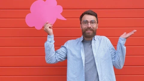 Surprised young man is holding a speech bubble, looking at camera and smiling Stock Footage 111840510