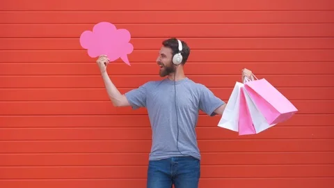 Surprised young man is holding a speech bubble, looking at camera and smiling Stock Footage 111862866