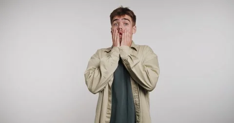 Surprised young man shows expression of shock in indoor setting with plain .. Stockbeeldmateriaal 326788526