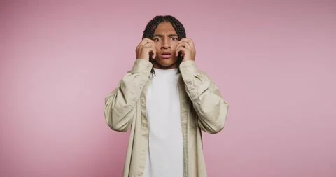 Surprised young man talking on the phone in front of a pink background with.. Stock-Footage 326788226