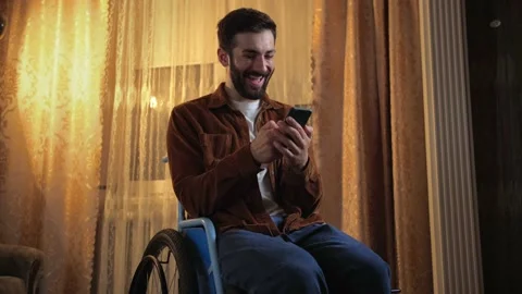 Surprised Young man in wheelchair using phone and laughing. An incapacitated Stock Footage 202116343