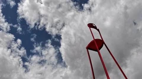 Surreal and Whimsical Timelapse of a Long Red Chair under Fast Moving Clouds Stock Footage 334583920