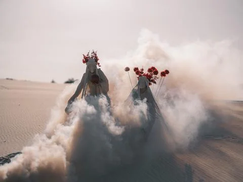 Surreal desert performance art two dancing women with artificial flowers an.. Foto stock