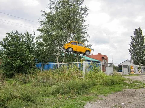 A surreal image features a yellow, floating car in an outdoor setting, possib Stock Photos