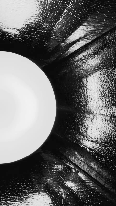 Surreal monochrome light orb shining through dimpled foil tunnel with reflective Stock Footage 327637273