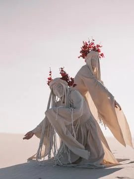 Surreal performance art two dancing women in white clothes on desert Stock-Fotos