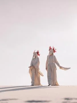 Surreal performance art two dancing women in white clothes on desert Foto stock