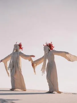 Surreal performance art two dancing women in white clothes on desert Foto stock