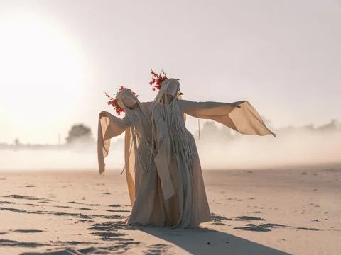 Surreal performance art two figures white costumes red flowers dancing dese.. Stock-Fotos