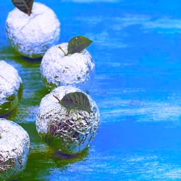 Surrealism Five apples in the shell foil with natural green leaves. Stock Photos