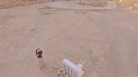 Surrealistic plot. A girl and a white piano on the background of a sand pit and Stock Footage 93010414