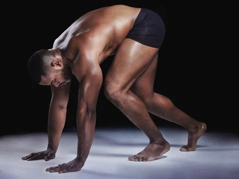 Surrender to desire. Studio shot of a young fit man stretching against a black Stock Photos