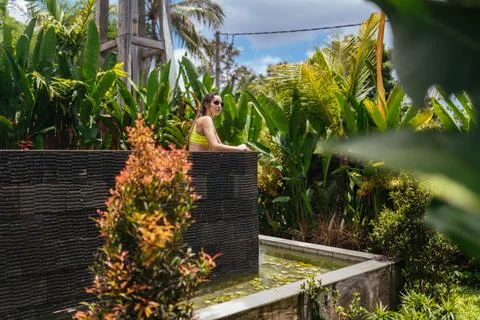 Surrounded by palm trees, a bunk pool on the upper tier stands a bather in a Stock Photos