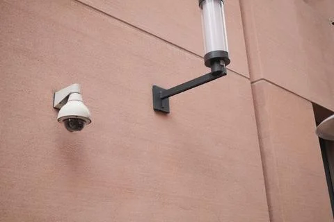 Surveillance camera and light on building wall Stock Photos