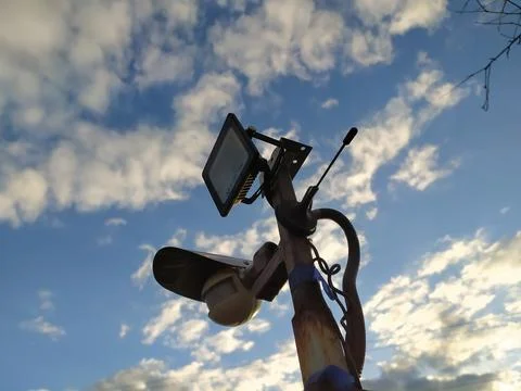 Surveillance camera on the background of the blue sky with clouds Stock Photos