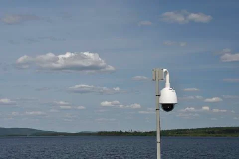 Surveillance camera with a blue sky with clouds and a lake in background Stock Photos