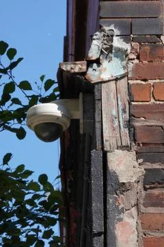 A surveillance camera on a broken wall area. Stockfoto's