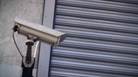 Surveillance camera in front of a closed security roll shutter system Video stock 229577247