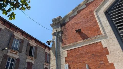 Surveillance camera on a lamp post between brick and stone facades Stock Photos