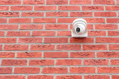 Surveillance camera mounted on red brick wall Stock Photos