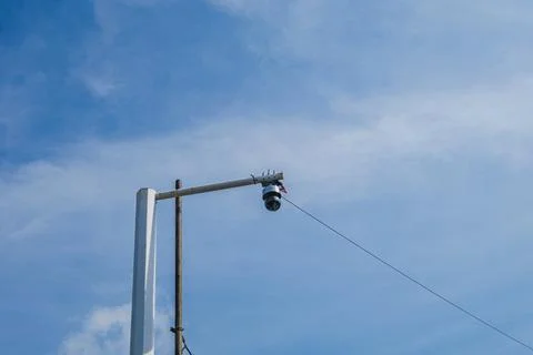 Surveillance camera mounted on a white pole against a blue sky Foto stock