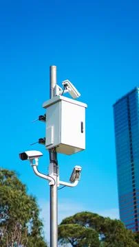 Surveillance camera system mounted on pole with modern building in background Stock Photos