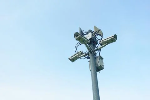 A Surveillance camera tower with multiple cameras and antennas against clear  Stock Photos