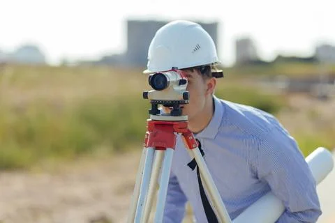 Survey engineer working with operating level survey cameras on construction site Stock Photos