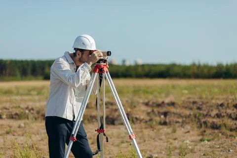 Survey engineer working with operating level survey cameras on construction site Stock Photos