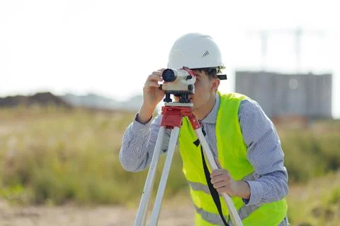 Survey engineer working with operating level survey cameras on construction site Stock Photos
