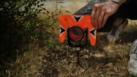 Surveyor adjusting orange prism target on tripod outdoors 動画素材 348029631